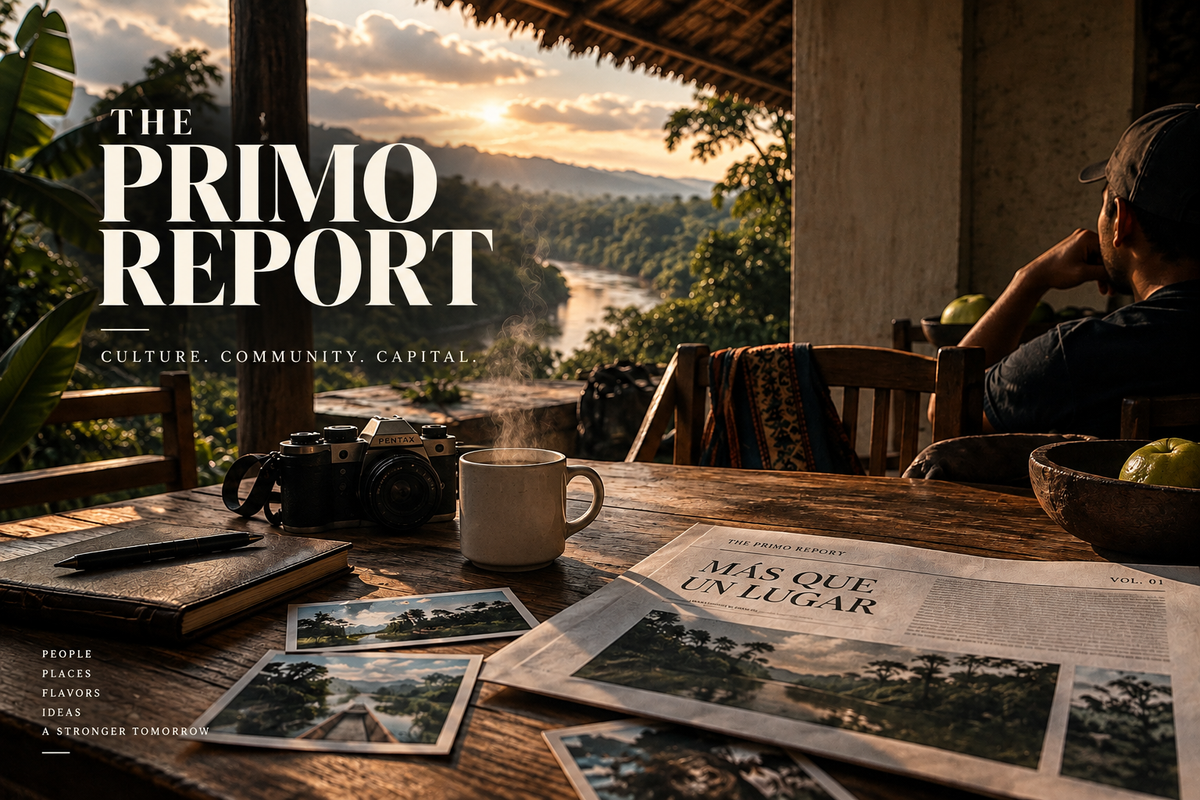 The Primo Report — Culture, Community, Capital. Coffee, a camera and a newspaper on a sunlit terrace overlooking a river.